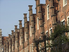 Detail of a historic brick building with distinctive gables and windows in sunny weather, Haarlem,