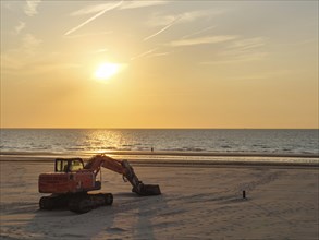A dredger in warm light on the beach during sunset, facing the calm sea, sunset on the beach of de