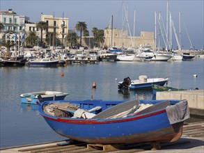 Harbour with fishing boats and sailing boats in the water, palm trees and buildings in the