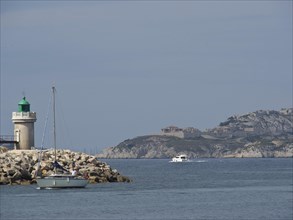 A lighthouse and boats on calm waters off a rocky coast, Marseille on the Mediterranean Sea with