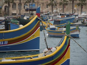 Detailed view of colourful fishing boats in the harbour of a historic town, palm trees and