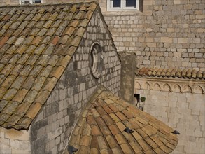 Old building with tiled roofs, stone walls and small windows, detailed view of the architecture,