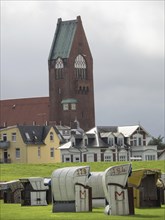Colourful beach chairs in a meadow in front of a village with a high church, Cuxhaven, Germany,