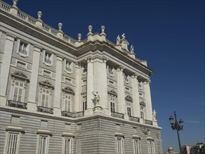 Large historic building with sculptures, balconies and ornate facades under a deep blue sky,