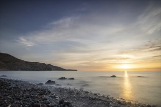 Sunrise with sea view in a lonely bay. rocky coast in warm colours. Landscape with a lava stone