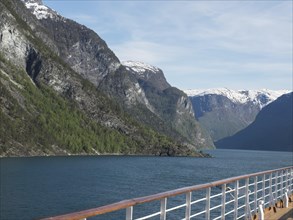 From the deck of a ship, a wide view of mountains and a deep fjord opens up, cruise through the