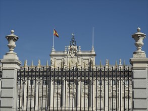 Historic building with decorative fence and a flag under a bright blue sky, Madrid, Spain, Europe