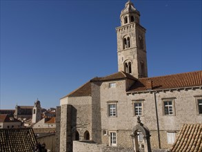Historic stone buildings and a tall tower under a clear blue sky, the old town of Dubrovnik with