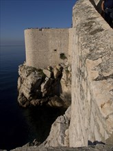 Massive fortress walls dropping down to the rocky coast, the old town of Dubrovnik with historic