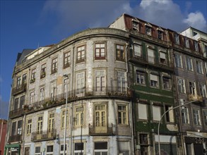 Large building with decorative facade and many windows, under a blue sky, old houses in the