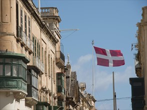 Historic buildings with a waving flag under a blue sky, Valetta, Malta, Europe