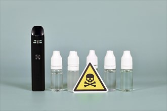 Bottles with liquid solutions and electronic cigarettes with toxic skull warning sign
