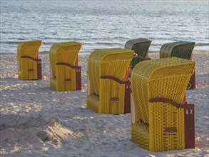 Yellow beach chairs on a sandy beach with a view of the sea in calm light conditions, autumn