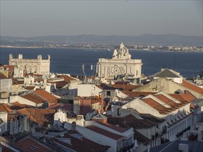 Sunset over the city with red roofs and sea view, view of the historic centre of Lisbon by the