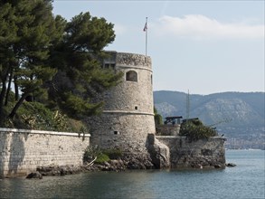 Historic fortress by the sea, with stone walls and flag, surrounded by wooded hills, la seyne sur