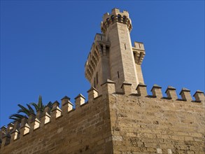 Tower and walls of a medieval sandstone fortress against a blue sky, palma de mallorca on the