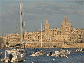 Harbour at sunset with sailing boats and a historic town in the background, Valetta, Malta, Europe