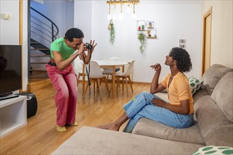 Gay man posing for his boyfriend taking photos with camera at home