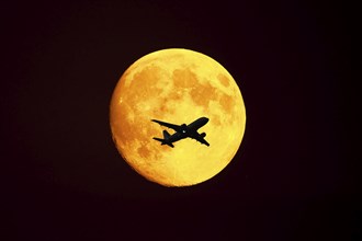 FOTOMONTAGE, Passenger plane flies in front of the moon