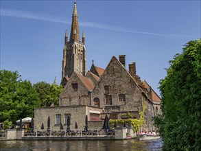 Historic building on the water canal, with tower and brick architecture under a clear blue sky,
