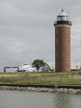 Lighthouse and surrounding buildings in a harbour area under a cloudy sky, Cuxhaven, Germany,