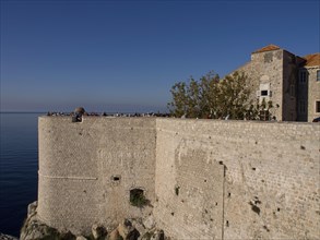 Historic coastal wall in front of a clear blue sky with a view of the sea, the old town of