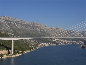 Wide angle shot of a bridge connecting a coastal town with houses and mountains, the old town of