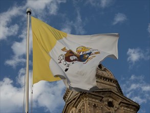 A yellow and white flag with symbols waving in the wind against a blue sky, Valetta, Malta, Europe