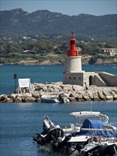 A picturesque harbour with boats and a red lighthouse against a mountain backdrop, la seyne sur