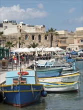 Boats in the harbour next to a lively town with waterfront promenade, restaurants and historic