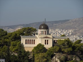 Historic building on a hill surrounded by trees overlooking a city, Ancient building with columns