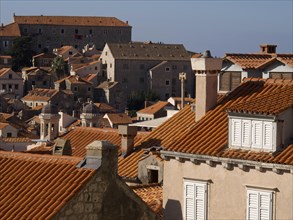 View of the typical red roof tiles of the old town houses with clear blue sky in the background,