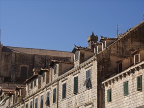 Historic buildings with tiled roofs and green shutters under a blue sky, the old town of Dubrovnik