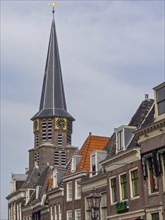 Church tower with clock and surrounding historic buildings under a blue sky, historic houses in