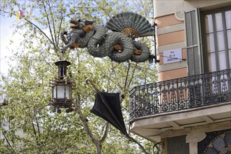 Barcelona, Catalonia, Spain, Europe, Dragon statue carrying a decorative lantern and an umbrella in