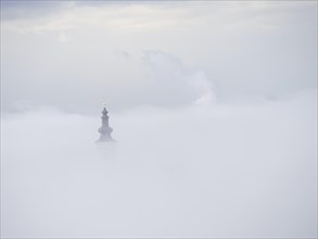 Church tower rises out of the morning mist, Frauenberg pilgrimage church, near Leibnitz, Styria,