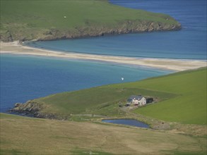 Secluded beach with a small house surrounded by green hills and blue sea under a clear sky, Green