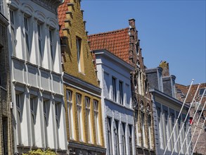 Row of historic buildings with ornate gables under a clear blue sky, historic houses and churches