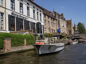 Scenic canal landscape with historic buildings, boats and clear blue sky, historic house facades in