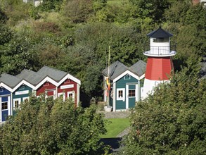 Small colourful houses and a lighthouse embedded in a green natural landscape, Heligoland, Germany,