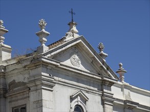 Detailed view of a historic building with architectural details and a cross under a clear sky,