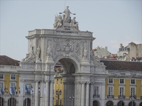 Triumphal arch with elaborate sculptures and decorations, surrounded by historic buildings, Lisbon,