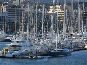 Harbour full of yachts and boats, surrounded by urban skyline with masts rising into the sky, palma