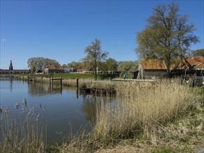 Small harbour with traditional buildings surrounded by reeds under a blue sky on a spring day,