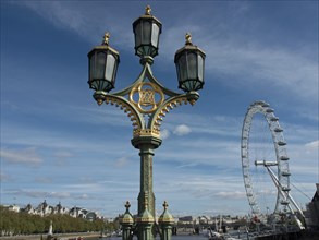 Decorated street lamp against a clear sky with the London Eye in the background, London, England,