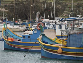 Maltese fishing boats in the harbour surrounded by other boats on calm waters, colourful boats in a