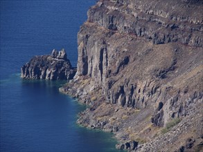 The rugged cliffs along a coastline of clear blue water, The volcanic island of Santorini with blue