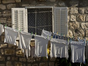 Laundry hanging on a line in front of a window with white-painted shutters, the old town of
