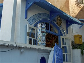 Traditional cafe with blue and white facade, postcard stand and lantern, cosy atmosphere, Tunis in
