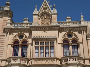 A historic building with an elaborately designed facade and balconies, the town of mdina on the